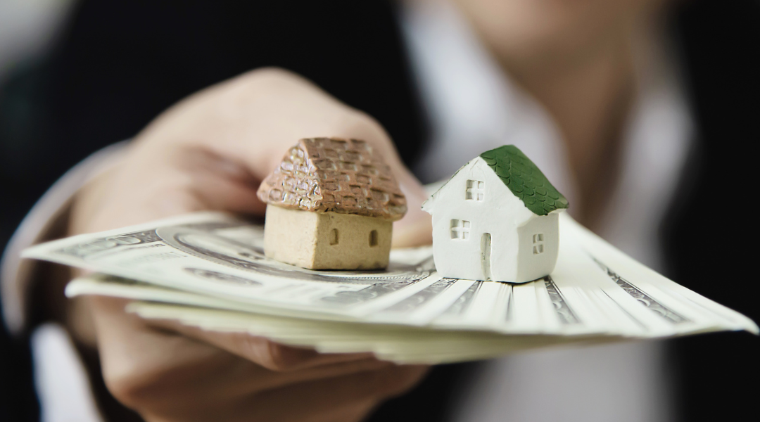 person holding our money with tiny ceramic house on it