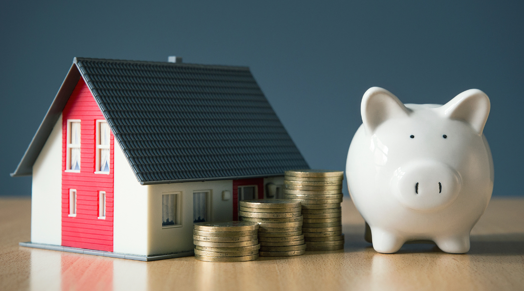 piggy bank with coins next to toy house