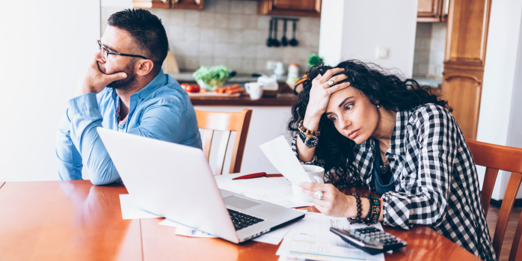 Frustrated husband and wife look over paperwork at kitchen table as they face issues after using a quitclaim deed. 